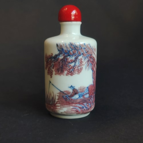 porcelain snuffbottle decorated in copper red and blue under cover of a fisherman in a landscape
China 19th century